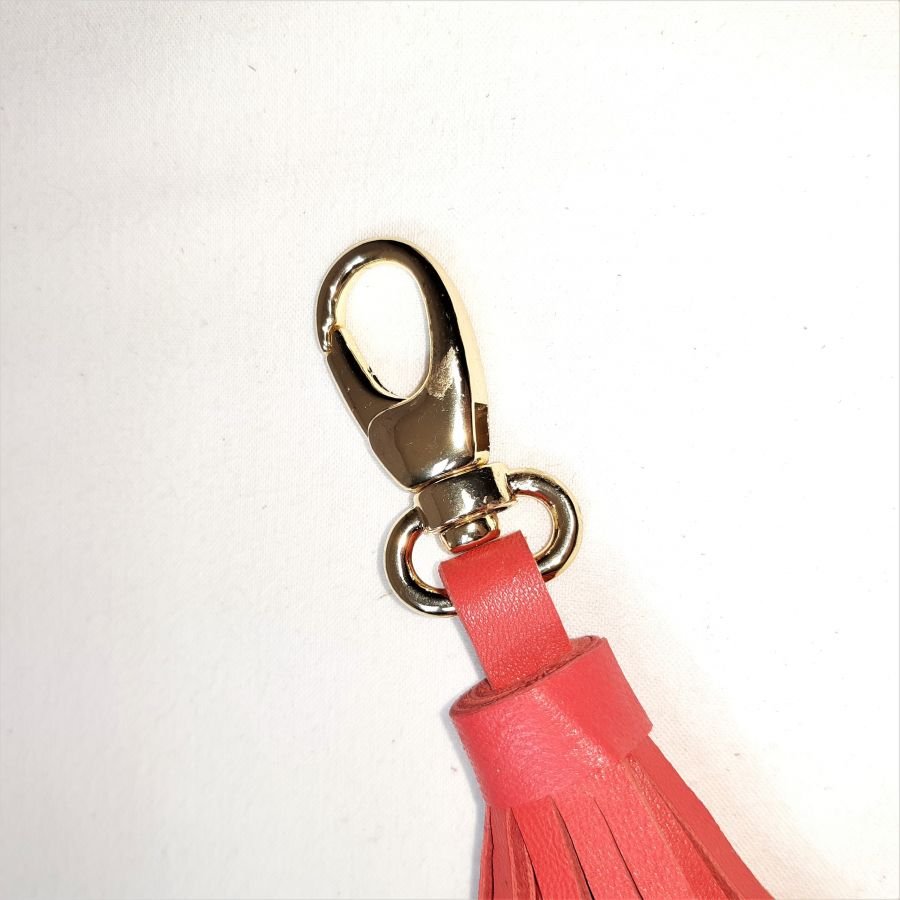 Tasjuweel met lamsleren pompon in oranjerode kleur.