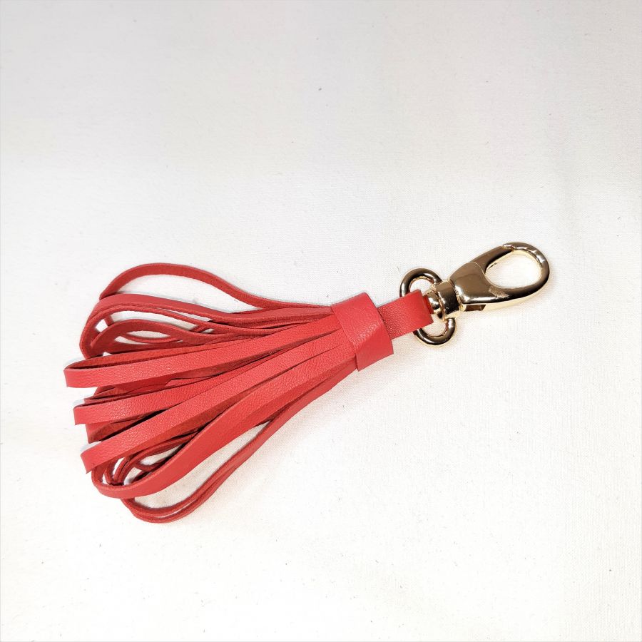 Tasjuweel met lamsleren pompon in oranjerode kleur.